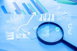 Magnifying glass and documents with analytics data lying on tabl