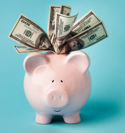 Pink piggybank stuffed with dollar bills spending
