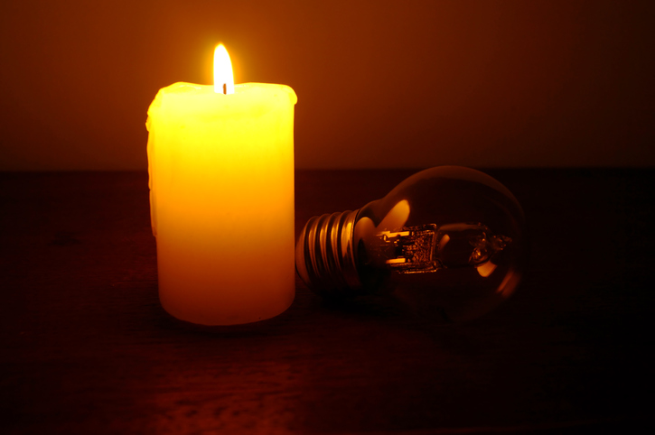 Burning candle and lamp on desktop in darkness