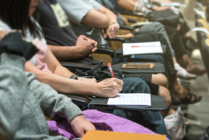 Close up shot of woman hand writing on the paper at the table in the conference hall or seminar meeting, business and education concept