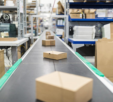 Cardboard boxes on conveyor belt at distribution warehouse