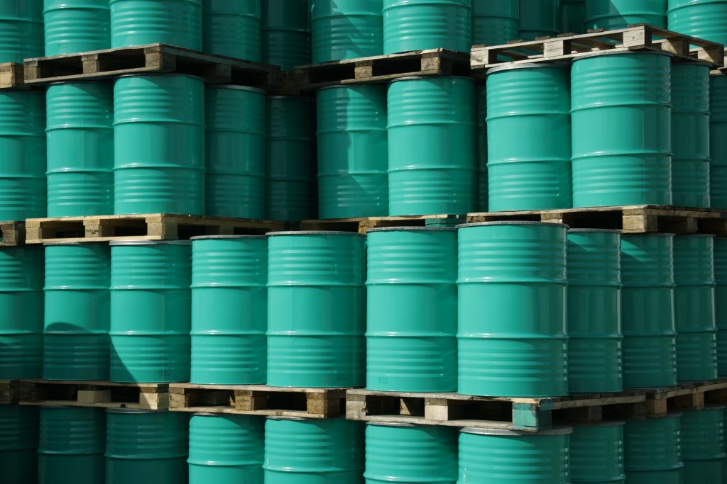Green barrels stacked high filled with oil