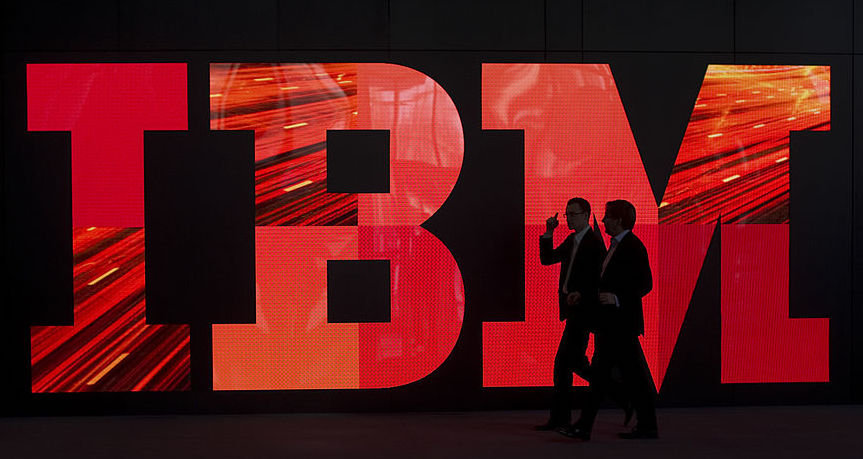 Two men walk past an IBM logo during pre